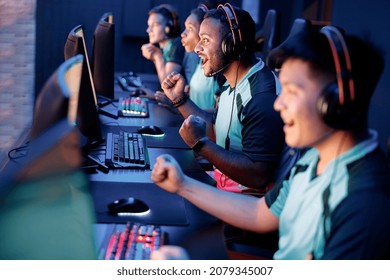 Team of professional esport gamers with happy man in focus playing in video games on cyber games tournament indoors - Shutterstock ID 2079345007