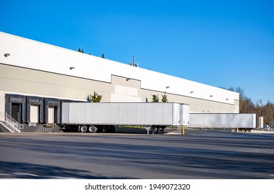 Team of professional freight commercial dry van semi trailers without industrial big rig semi trucks standing at row on business parking lot loading cargo at warehouse dock gates