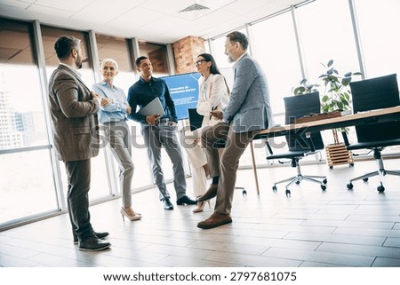 A team of professionals collaboratively discussing a project in a bright, stylish office with formalwear style.