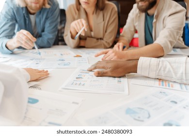 Team of professionals gathered around a table, collaborating and strategizing while reviewing financial reports and data visualizations - Powered by Shutterstock