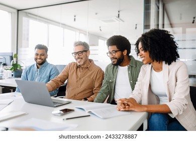 A team of professionals shares a cheerful moment around a laptop, signifying a successful collaboration and productive work environment. Colleagues engage in a lively exchange of ideas in an office - Powered by Shutterstock