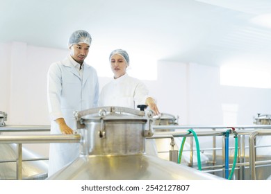 Team of quality control officers or factory engineers are inspecting inside the beverage manufacturing facility. Man and woman engineers working in a food production factory. - Powered by Shutterstock