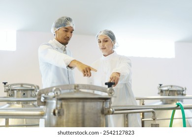 Team of quality control officers or factory engineers are inspecting inside the beverage manufacturing facility. Man and woman engineers working in a food production factory. - Powered by Shutterstock