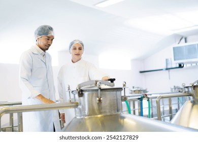 Team of quality control officers or factory engineers are inspecting inside the beverage manufacturing facility. Man and woman engineers working in a food production factory. - Powered by Shutterstock