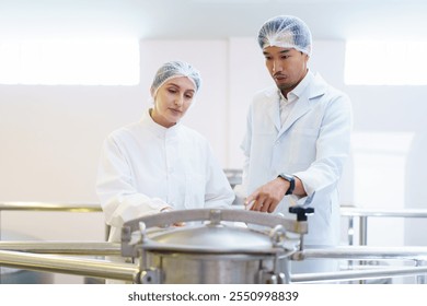 Team of quality control officers or factory engineers are inspecting inside the beverage manufacturing facility. Man and woman engineers working in a food production factory. - Powered by Shutterstock