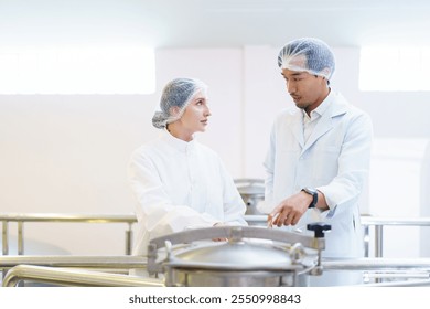 Team of quality control officers or factory engineers are inspecting inside the beverage manufacturing facility. Man and woman engineers working in a food production factory. - Powered by Shutterstock