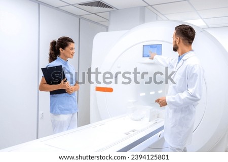Team of radiologists and doctors checking and preparing modern MRI scanning machine in hospital.