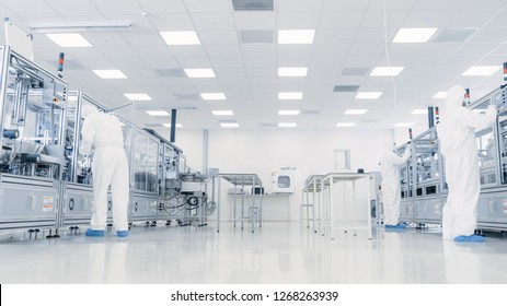 Team of Research Scientists in Sterile Suits Working with Computers, Microscopes and Industrial Machinery in the Laboratory. Product Manufacturing Process: Pharmaceutics, Semiconductors, Biotechnology