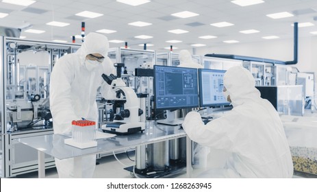 Team of Research Scientists in Sterile Suits Working with Computers, Looking Under Microscope and Industrial Machinery in the Laboratory. Product Manufacturing Process: Pharmaceutics, Semiconductors, 