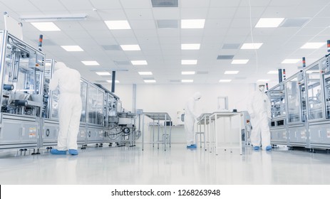Team of Research Scientists in Sterile Suits Working with Computers, Microscopes and Industrial Machinery in the Laboratory. Product Manufacturing Process: Pharmaceutics, Semiconductors, Biotechnology