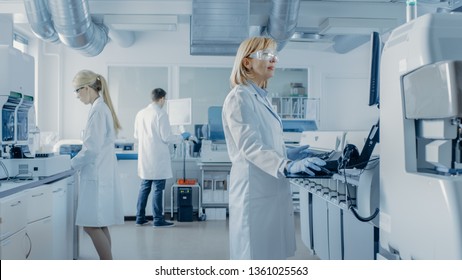 Team of Research Scientists Working On Computer, with Medical Equipment, Analyzing Blood and Genetic Material Samples with Special Machines in the Modern Laboratory.