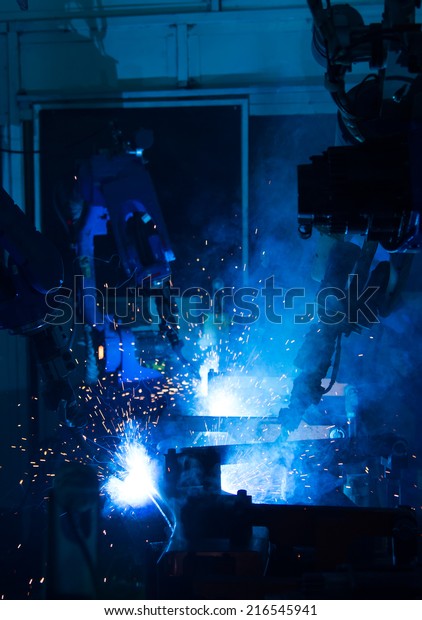 A\
team of robots welding in automobile parts\
industry.