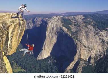 Team Of Rock Climbers Struggle Up A Challenging Cliff.