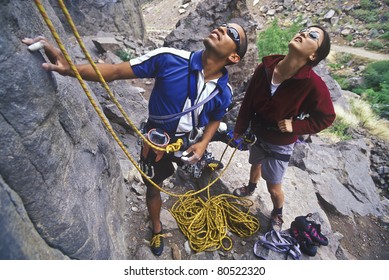 Team Of Rock Climbers Struggle To Reach The Summit Of A Steep Pinnacle.