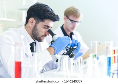 Team Of Scientist Research Working Together Conduct Experiments And Looks On Microscope In Modern Laboratory / Scientists In Lab Biochemistry Genetics Forensics Microbiology And Test Tube Male Doctor