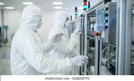 Team Of Scientists In Sterile Protective Clothing Work On A Modern Industrial 3D Printing Machinery. Pharmaceutical, Biotechnological And Semiconductor Creating / Manufacturing Process.