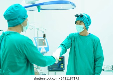 Team of specialist doctor making a handshake in operating room after successfully done on critical surgery. Doctors doing a handshake together after finished a surgery. Medical profession portrait. - Powered by Shutterstock