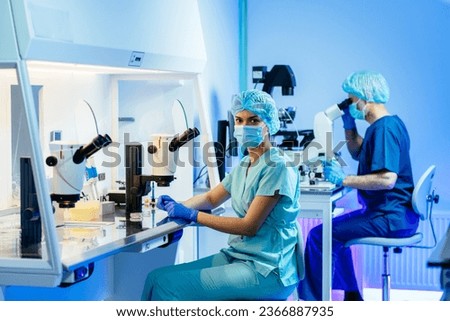 Team of specialists using advanced technology equipment in modern embryology laboratory.