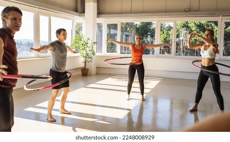 Team Sport group of people doing hula hoop in step waist hooping forward stance in fitness gym for healthy lifestyle concept.