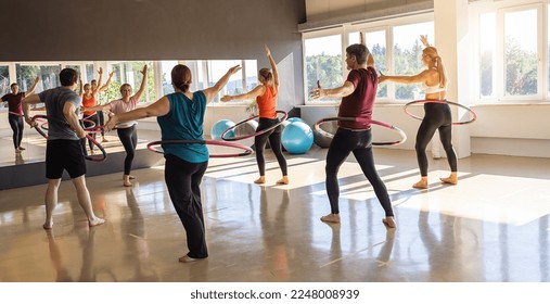 Team Sport Sporty women and men  exercising with Hula hoop in fitness gym for healthy lifestyle concept.