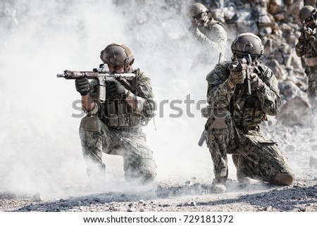 Team squad of special forces in action in the desert among the rocks covered by smoke screen