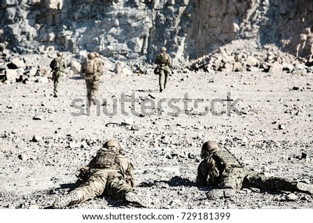 Team squad of special forces in action in the desert among the rocks