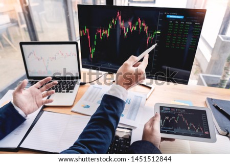 Team of stockbrokers Discussing with display screens Analyzing data, graphs and reports of stock market trading for investment 
