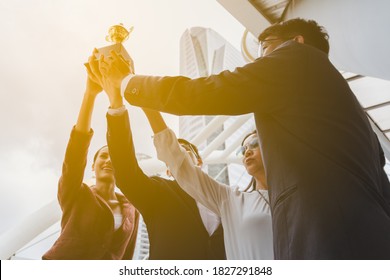 Team Success Of Asian Young Businessman And Businesswoman Raise Up The Trophy And Celebrate . Teamwork Of Successful Outdoors. Together.