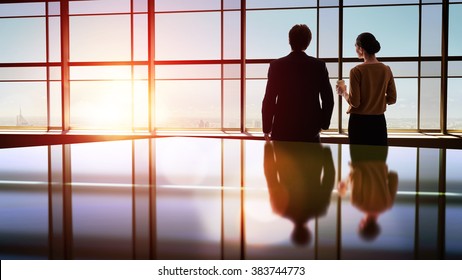 Team Of Successful Business People. Two Businessmen Resting And Talking In The Office. Man And Woman Look At The City From The Window Of The Business Center.
