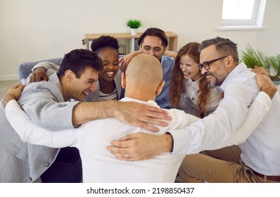 Team of successful positive colleagues laughing and hugging while standing in circle in office. Cheerful business colleagues celebrate their success together. Concept of cohesion and teamwork. - Powered by Shutterstock