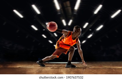 Team supporting. African-american young basketball player in action and motion in flashlights over dark gym background. Concept of sport, movement, energy and dynamic, healthy lifestyle. Arena's - Powered by Shutterstock