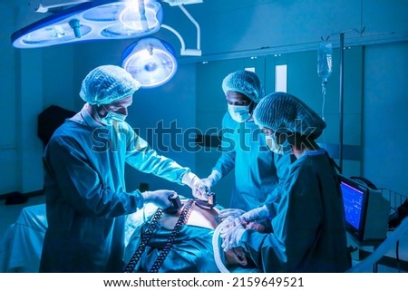 Team of surgeon doctor using defibrillator to give electrical shock wave to patient heart who is suffering from cardiac arrest in emergency surgical room for healthcare concept