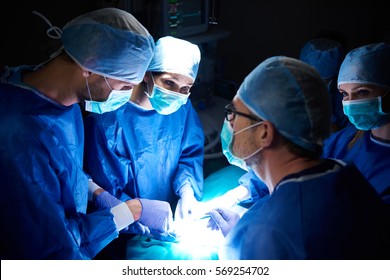 Team Of Surgeons In The Dark Operating Room