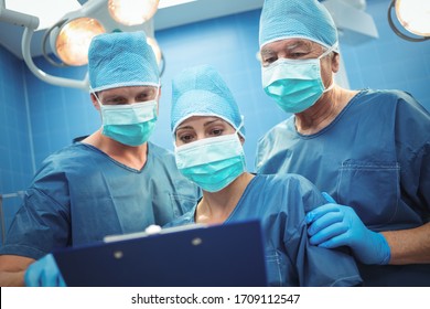 Team of surgeons discussing over clipboard in operation theater at hos. Healthcare workers in the Coronavirus Covid19 pandemic
pital - Powered by Shutterstock