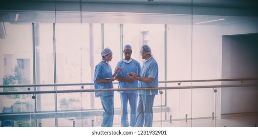 Team of surgeons discussing over digital tablet in hospital corridor - Powered by Shutterstock