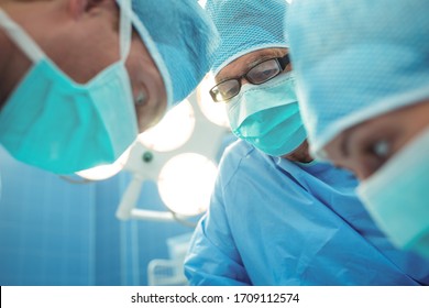 Team of surgeons performing operation in operation theater at hospital. Healthcare workers in the Coronavirus Covid19 pandemic

