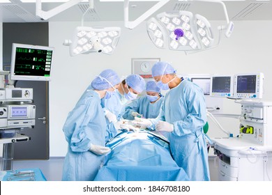 A team of surgeons wearing surgical suits while performing an operation in a fully quipped operating room - Powered by Shutterstock