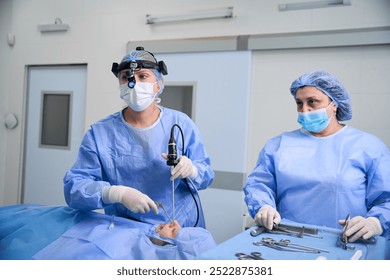 Team of surgeons working in a sterile operating room - Powered by Shutterstock