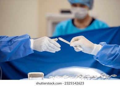 Team of surgery doctor in Operating Room hold hands scalpel surgical blade give to Surgeons During Operation. surgeons assistance in green gown coat give scalpel surgical blade to doctor - Powered by Shutterstock