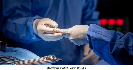 Team of surgery doctor in Operating Room hold hands scalpel surgical blade give to Surgeons During Operation. surgeons assistance in green gown coat give scalpel surgical blade to doctor - Shutterstock ID 2364699161