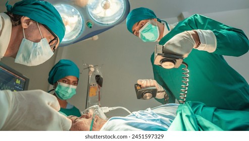 Team of surgery doctor using defibrillator pump chest heart patient to save life while medical surgery in operating room at emergency CPR. Defibrillator in surgeon specialist hand. - Powered by Shutterstock