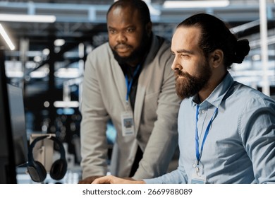 Team of technicians in data center using PC to update storage arrays software, configuring network virtualization. Teamworking colleagues in server room using computer to verify settings