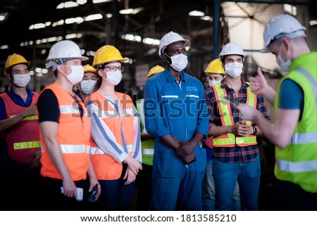 A team of technicians, foreman and engineers Accepting assignments from a manager or supervisor In the morning meeting before work In which everyone wear surgical masks to prevent the coronavirus