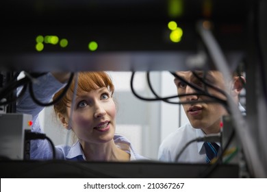 Team of technicians talking and looking at server in large data center