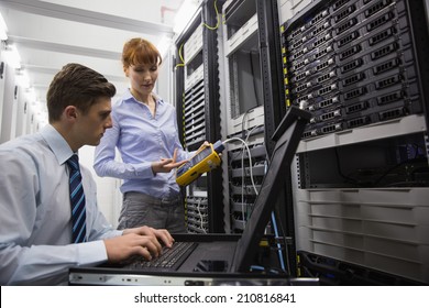 Team of technicians using digital cable analyser on servers in large data center