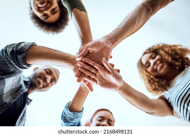 The team that dreams continuously achieves. Low angle shot of a group of businesspeople joining their hands together in a huddle.