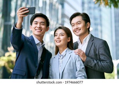 Team Of Three Asian Businesspeople Taking A Selfie In Downtown Financial District Of Modern City