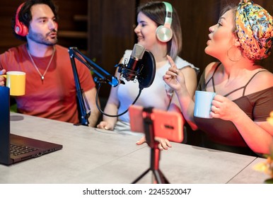 A team of three caucasian deejay having conversation about art, music and culture in their streaming vlog podcast while drink american cofee. - Powered by Shutterstock