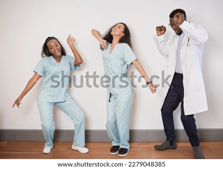 Team of three medical professionals dance on a break, doctor having fun