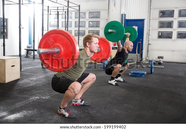 Team trains squats at\
fitness gym center